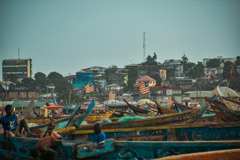 Vibrant scene of fishing boats and urban skyline in Monrovia, Liberia.