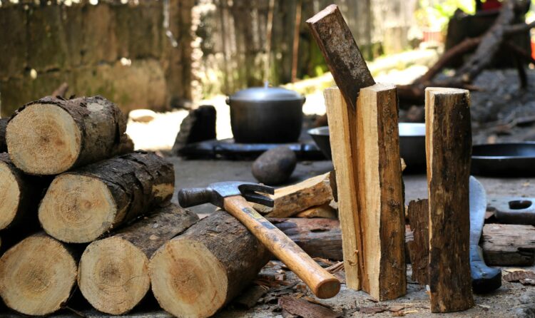 Chopped firewood with hammer outdoors, showcasing rustic tools in a natural setting.