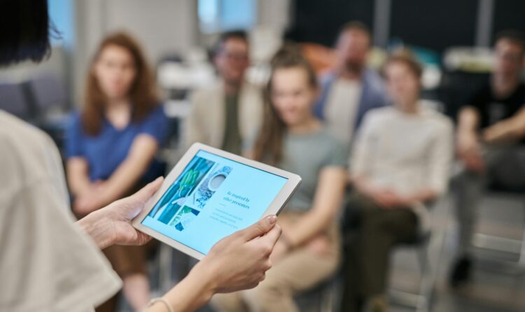 Business seminar with participants focused on a tablet presentation in an office setting.